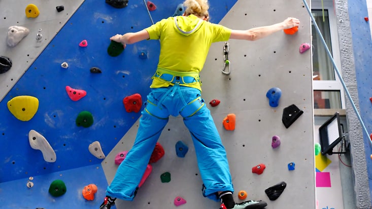 Kletterwand mit Frau beim Hochklettern.