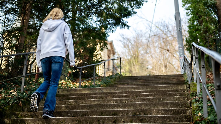 Frau geht Treppe hinauf.